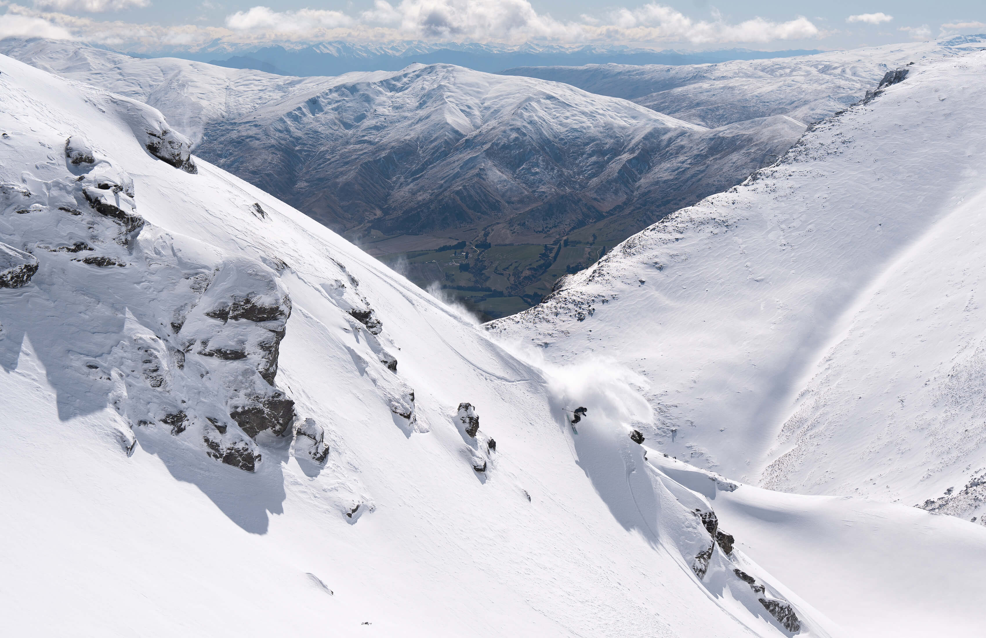 Skier descending a steep, snow-covered off-piste mountain slope at The Remarkables.